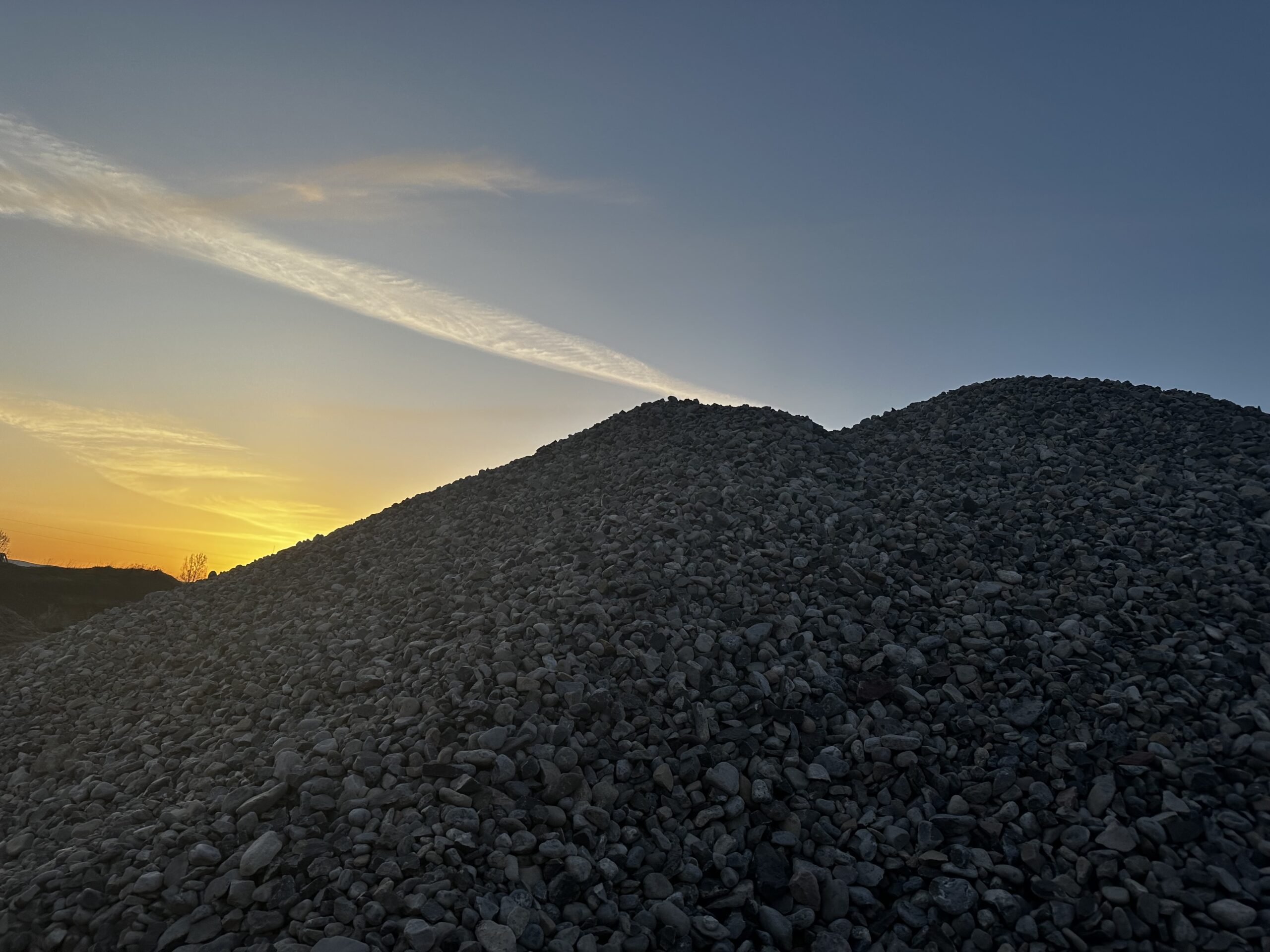 Darby Pit, Gravel & Trucking - We specialize in providing top-quality materials such as dirt, sand, gravel, and crushed stone, perfect for all your excavation and landscaping needs. Our range of services caters to home builders and developers focused on constructing roads, paths, driveways, and foundations. With our reliable trucking services for transportation and delivery, we ensure your project’s success from start to finish. Picture this: silhouettes of gravel mounds bathed in the golden hues of a twilight sunset—a testament to the raw beauty and utility of our materials in shaping your vision.