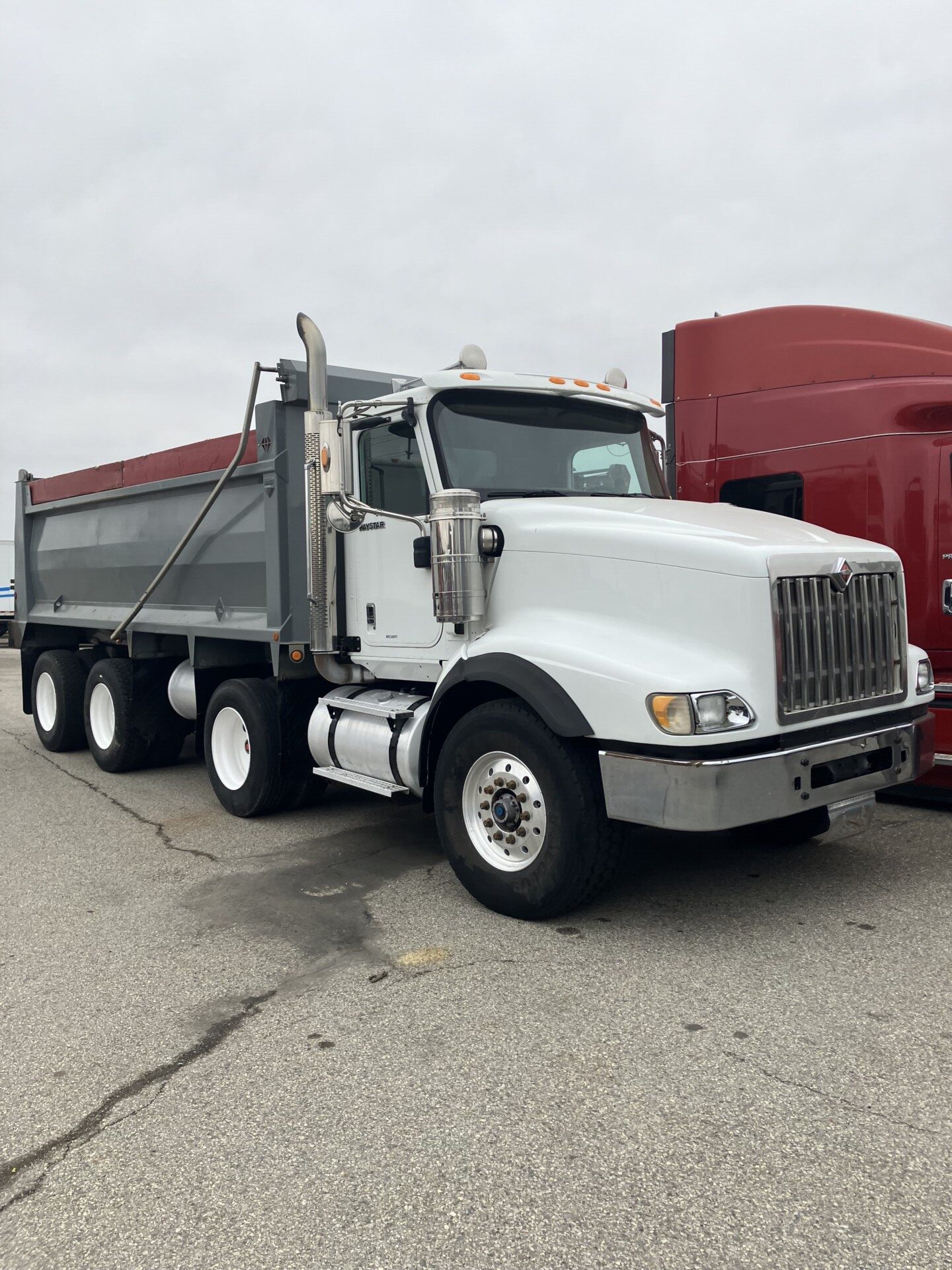 Darby Pit, Gravel & Trucking - We specialize in providing high-quality materials such as dirt, sand, gravel, and crushed stone, essential for all your excavation, landscaping, home construction projects. Whether you're building roads, paths, driveways, or foundations, we've got you covered. Our services include reliable trucking solutions to ensure timely delivery of these materials right to your site.
Picture this: A sturdy white dump truck with a grey cargo bed is parked next to a sleek red vehicle on an overcast day—ready and waiting to transport the materials you need efficiently and effectively. Trust our expertise to support your building needs from start to finish.