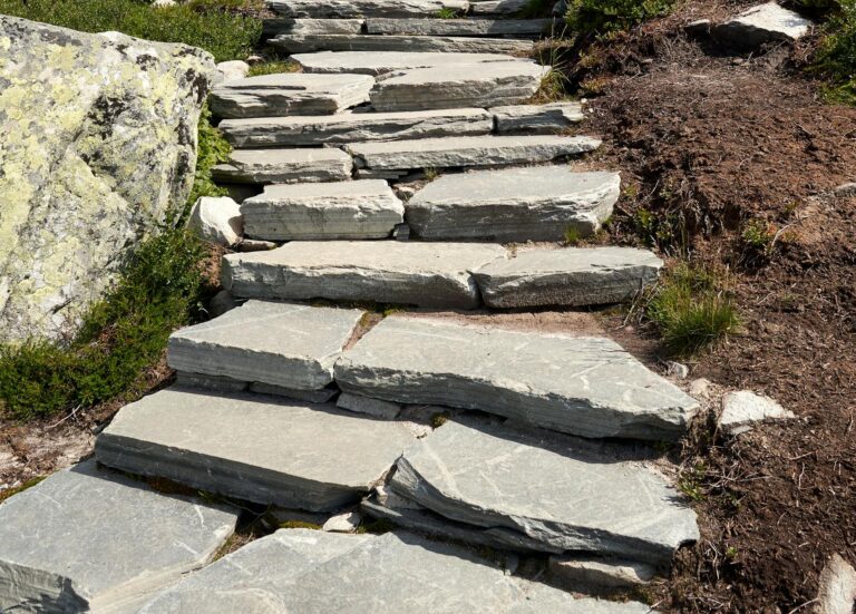 Stone steps leading through a lush mountain landscape under a clear blue sky.